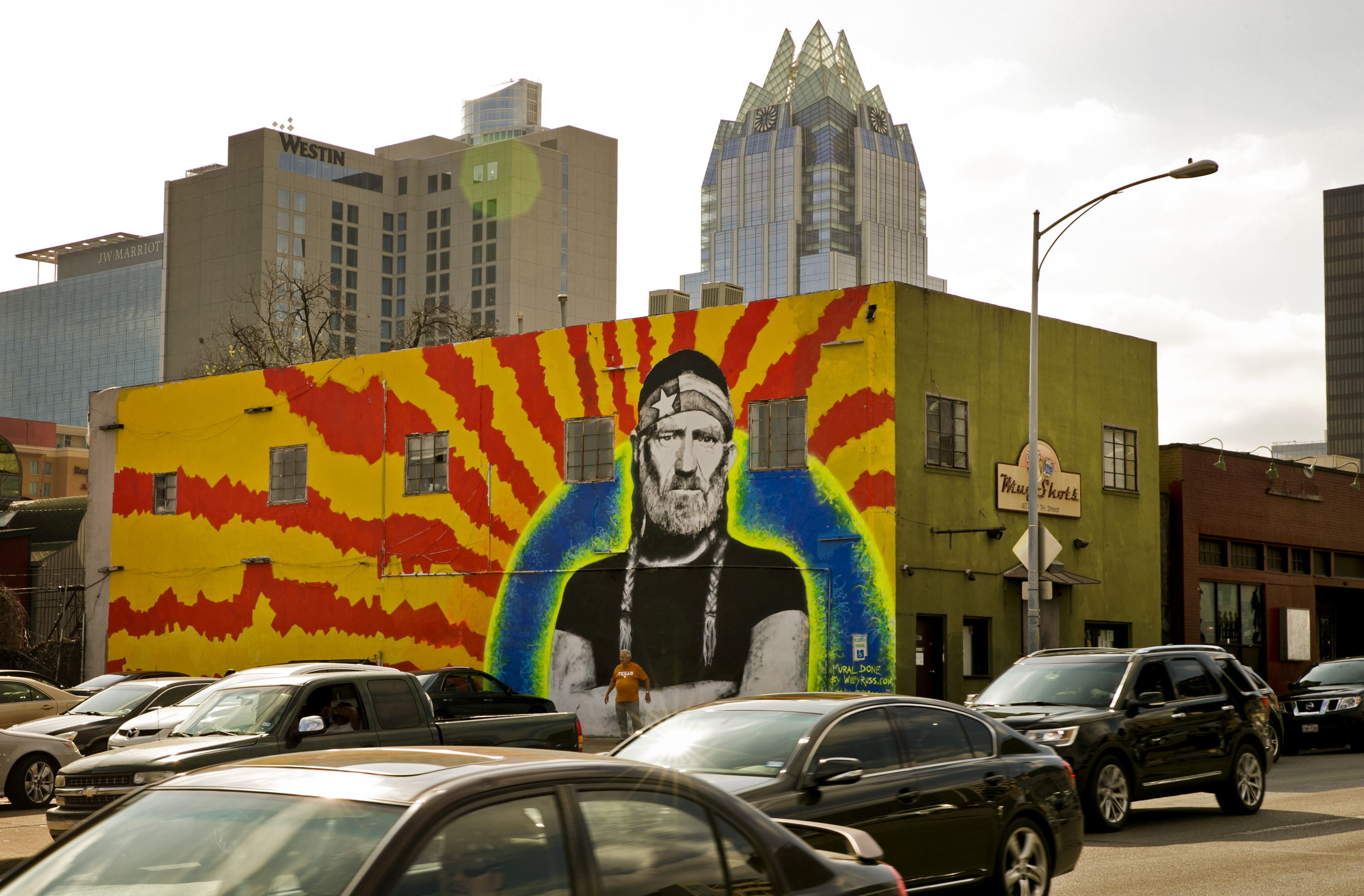 A 60-foot-by-20-foot mural of Willie Nelson looms over traffic on East Seventh Street at Neches Street on Monday, February 22, 2016. Austin artist Wiley Ross completed the mural Sunday after a week of painting. Rudy Duran is dwarfed by the mural while posing for a photo. "He is Texas, as far as I'm concerned," said Duran, who came to look at the mural as soon as he heard about it. JAY JANNER / AMERICAN-STATESMAN